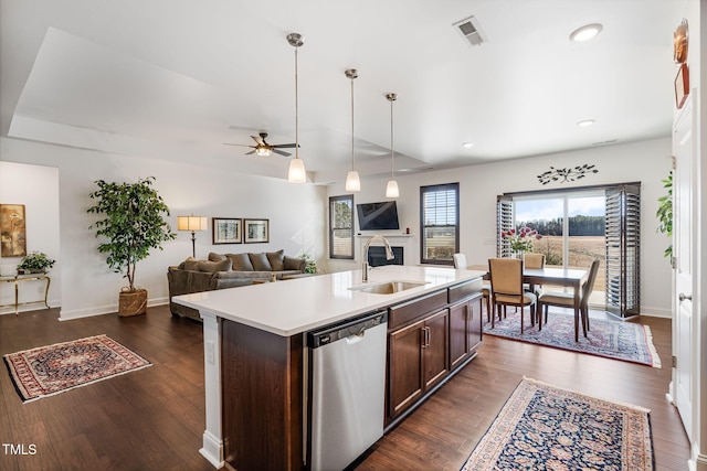 kitchen with dark brown cabinetry, sink, hanging light fixtures, dishwasher, and an island with sink