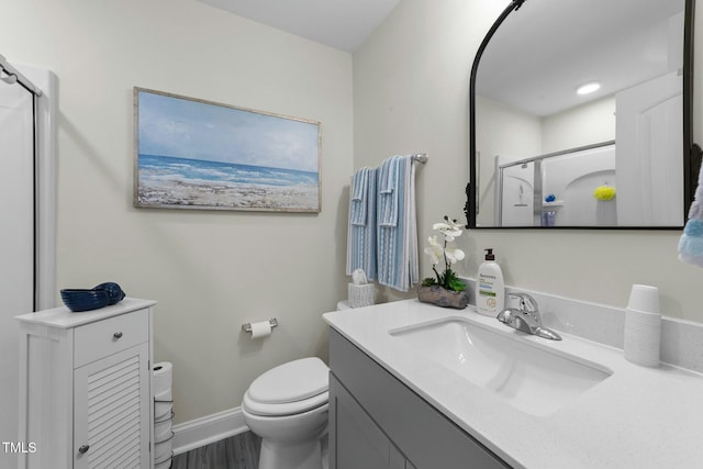 bathroom with hardwood / wood-style floors, vanity, toilet, and walk in shower