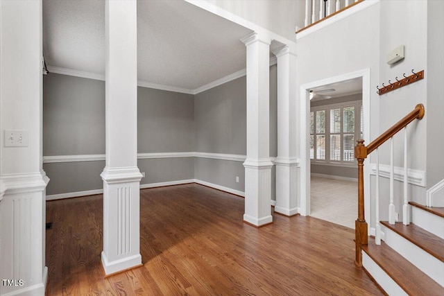 unfurnished living room featuring wood-type flooring, ornamental molding, and ornate columns