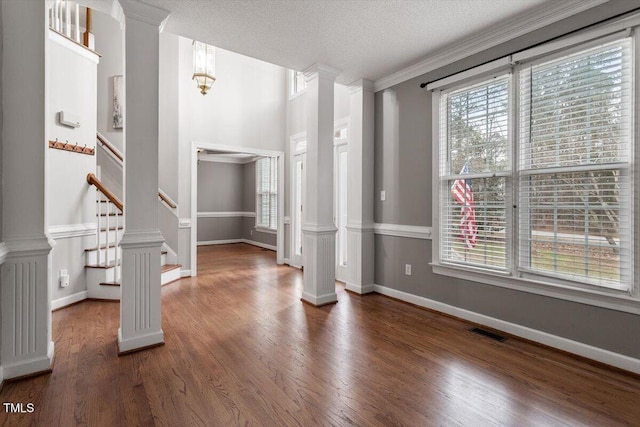 foyer featuring ornamental molding, decorative columns, dark hardwood / wood-style floors, and a textured ceiling