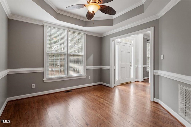 empty room featuring hardwood / wood-style flooring, crown molding, and a tray ceiling