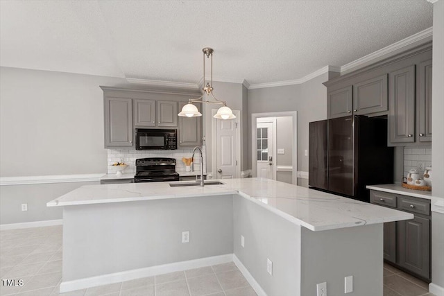 kitchen featuring light stone counters, sink, an island with sink, and black appliances