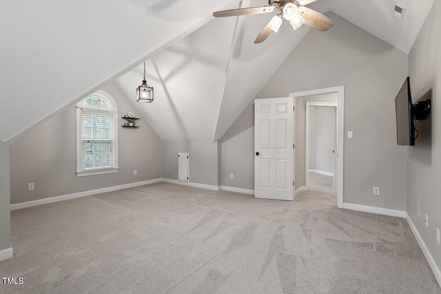 additional living space featuring lofted ceiling, light colored carpet, a textured ceiling, and ceiling fan