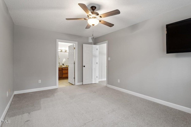 unfurnished bedroom with ensuite bathroom, light carpet, ceiling fan, and a textured ceiling