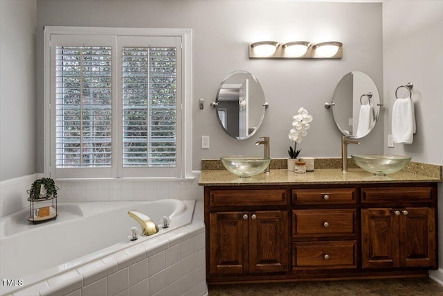 bathroom featuring tiled tub and vanity