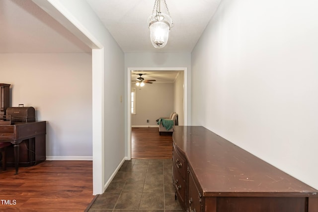 corridor featuring dark tile patterned floors and baseboards