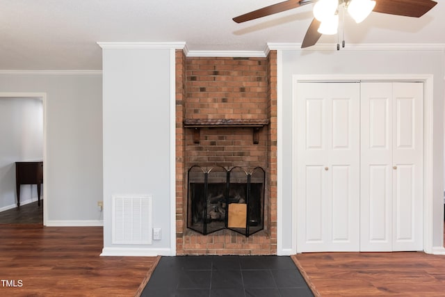 living room with visible vents, ornamental molding, dark wood-type flooring, a brick fireplace, and baseboards