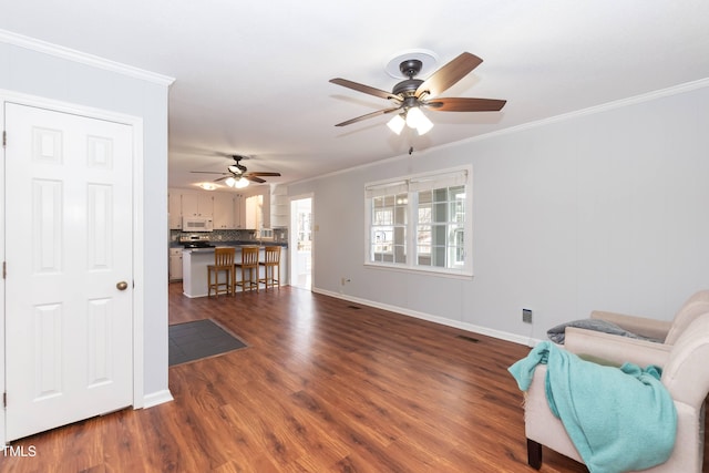 sitting room with ornamental molding and dark wood-style flooring