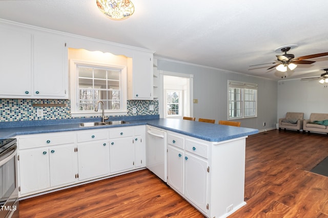 kitchen with white cabinets, dark countertops, a peninsula, white dishwasher, and a sink