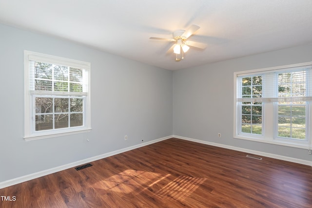 unfurnished room with dark wood-style flooring, visible vents, and baseboards