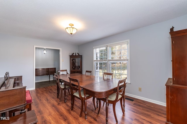 dining area with dark wood-style floors, baseboards, and visible vents