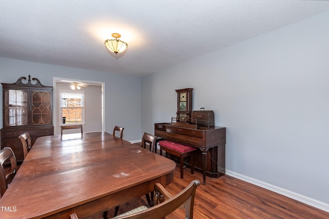 dining area featuring a textured ceiling, baseboards, and dark wood-type flooring