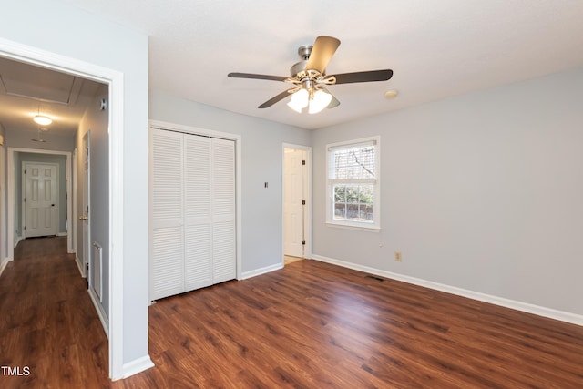 unfurnished bedroom featuring attic access, visible vents, baseboards, dark wood finished floors, and a closet