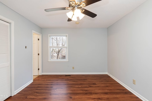 empty room with dark wood-style flooring, ceiling fan, and baseboards