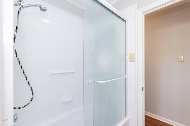 full bath with baseboards, an enclosed shower, and wood finished floors