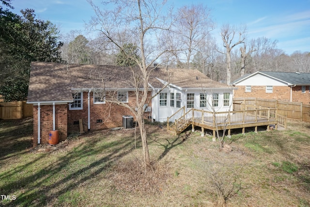 rear view of property featuring brick siding, central air condition unit, a lawn, a fenced backyard, and a wooden deck