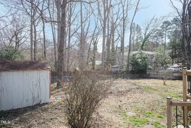 view of yard with a storage shed, an outbuilding, and fence