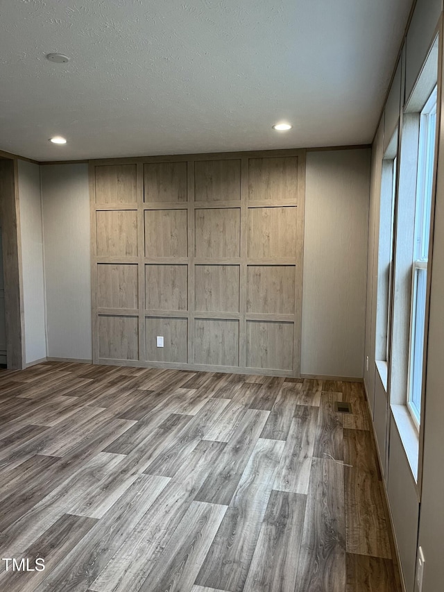 spare room with a textured ceiling and light hardwood / wood-style floors