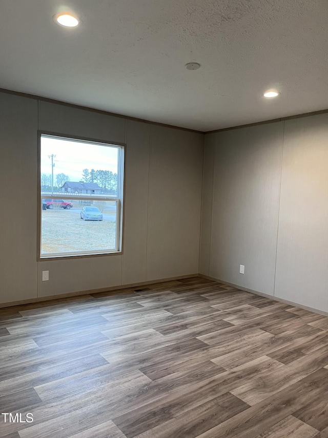 unfurnished room featuring light hardwood / wood-style flooring and a textured ceiling