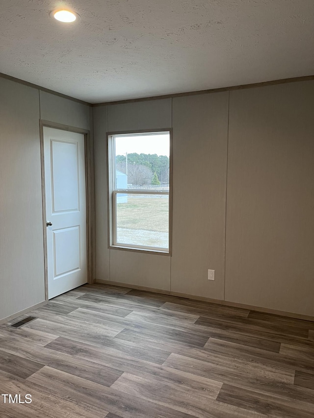 unfurnished room with a textured ceiling and light hardwood / wood-style flooring