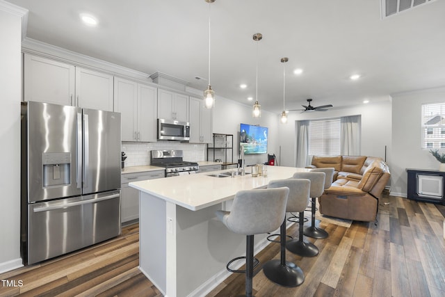 kitchen featuring pendant lighting, sink, a kitchen breakfast bar, stainless steel appliances, and an island with sink