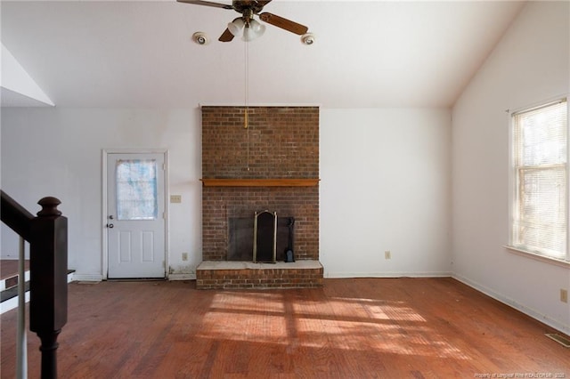 unfurnished living room featuring ceiling fan, lofted ceiling, hardwood / wood-style floors, and a brick fireplace