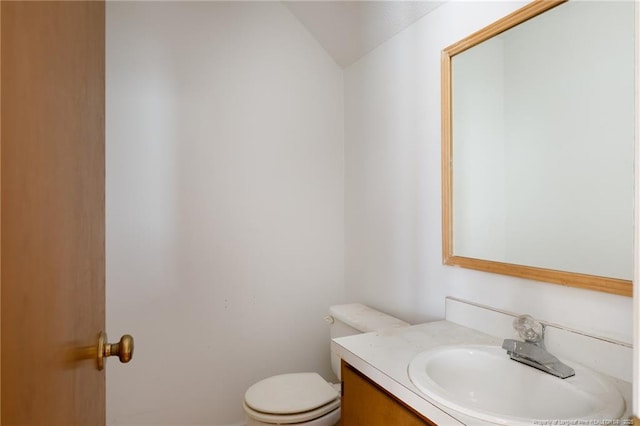 bathroom featuring lofted ceiling, toilet, and vanity