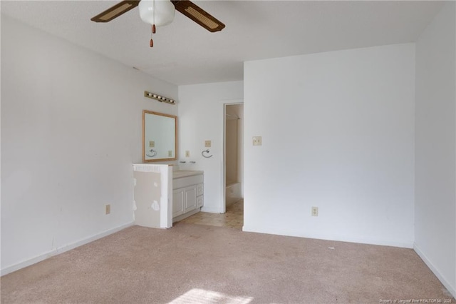 unfurnished bedroom featuring light carpet, ceiling fan, and ensuite bath