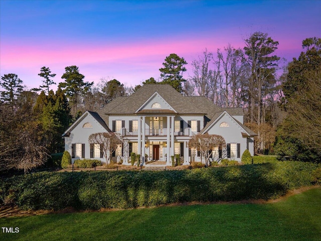 view of front of house featuring a balcony and a yard