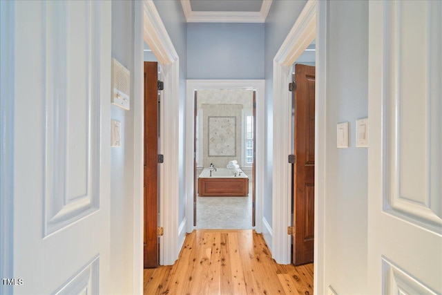 corridor featuring baseboards, light wood-style floors, and crown molding