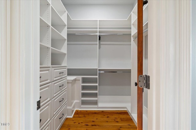 walk in closet with wood finished floors