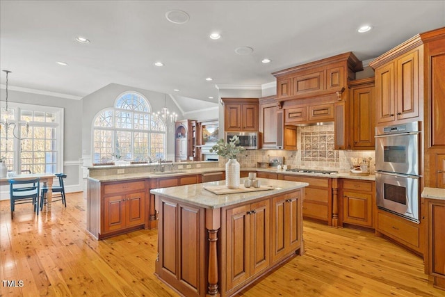 kitchen featuring a peninsula, hanging light fixtures, an inviting chandelier, and a center island