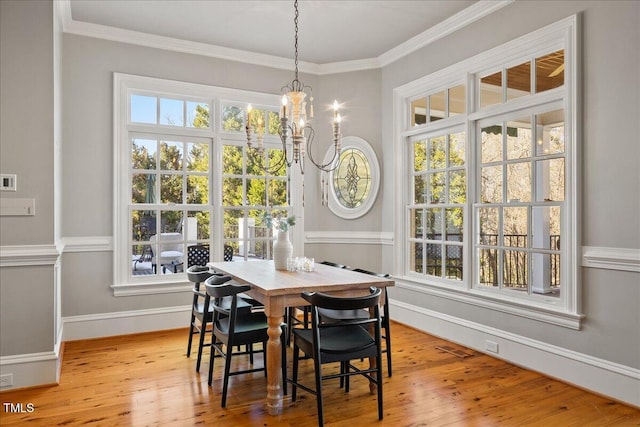 dining area featuring a chandelier, a healthy amount of sunlight, light wood-style flooring, and crown molding