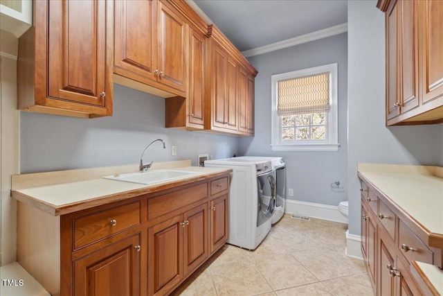 washroom with cabinet space, baseboards, ornamental molding, independent washer and dryer, and a sink