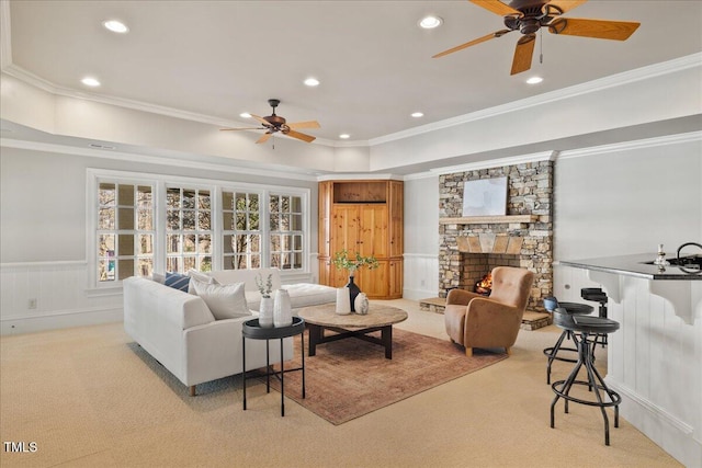 living area featuring crown molding, a fireplace, recessed lighting, light colored carpet, and wainscoting