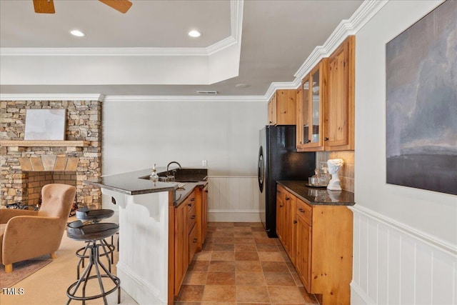 kitchen with a wainscoted wall, a breakfast bar, glass insert cabinets, and brown cabinets