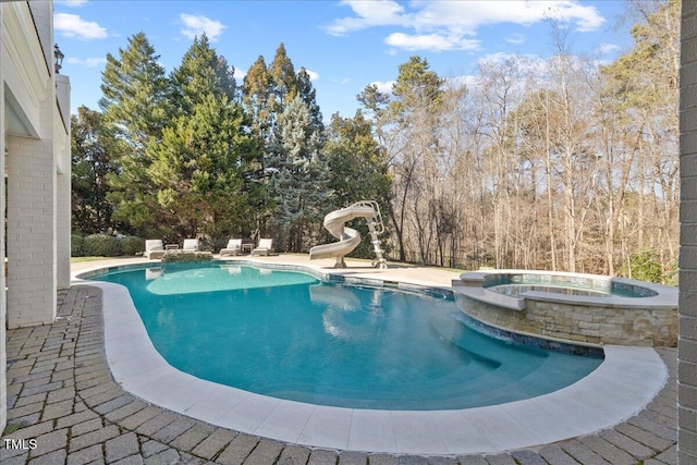 view of swimming pool featuring a pool with connected hot tub, a water slide, and a patio