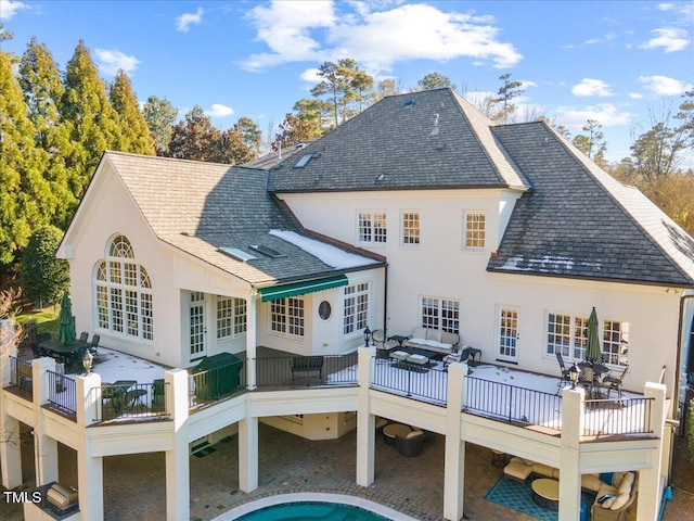 back of property with a shingled roof and outdoor lounge area