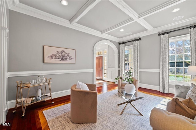 living area with arched walkways, coffered ceiling, wood finished floors, beamed ceiling, and crown molding