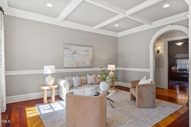 living room with baseboards, arched walkways, coffered ceiling, and wood finished floors