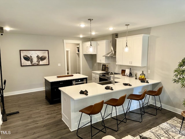 kitchen with wall chimney range hood, pendant lighting, white cabinets, and kitchen peninsula