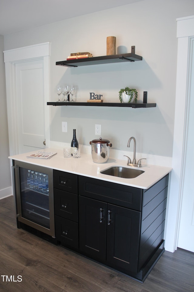 bar with sink, dark wood-type flooring, and beverage cooler