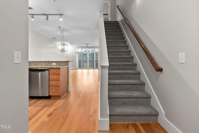 stairway featuring rail lighting and hardwood / wood-style floors