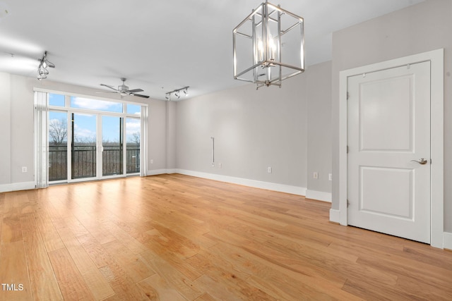 spare room featuring ceiling fan with notable chandelier, light hardwood / wood-style floors, and rail lighting