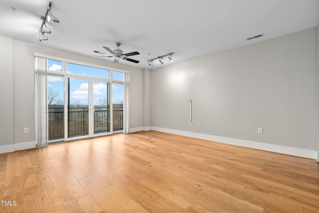 empty room featuring light hardwood / wood-style flooring, ceiling fan, and track lighting