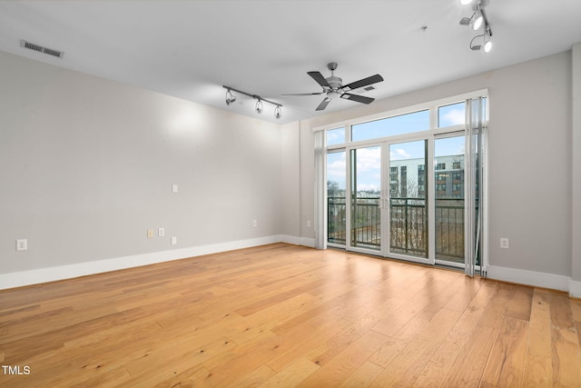 empty room featuring ceiling fan, rail lighting, and light hardwood / wood-style floors