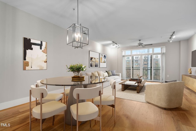 dining room with ceiling fan, rail lighting, and light hardwood / wood-style flooring