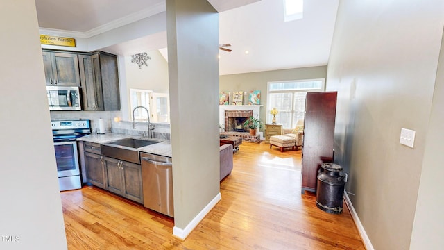 kitchen featuring sink, appliances with stainless steel finishes, light stone counters, dark brown cabinetry, and light wood-type flooring