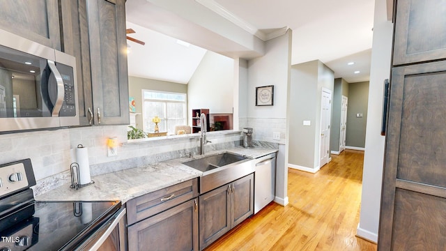 kitchen with light stone counters, sink, backsplash, and stainless steel appliances