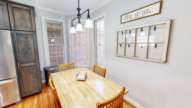 dining area with ornamental molding and light wood-type flooring